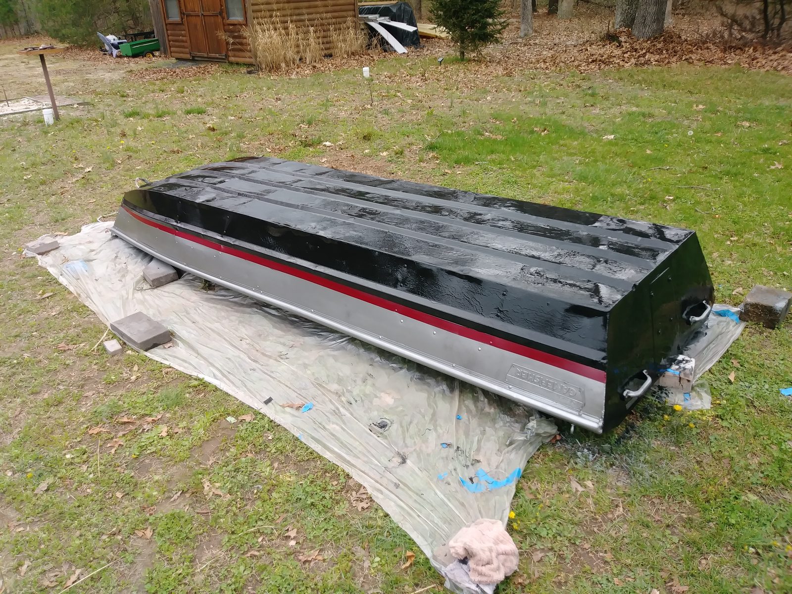 Hull flipped over with a glossy black coat and red pinstripe applied